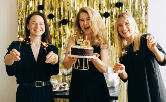 [Uber En="50th*birthday*party*games*with*three*women*celebrating*one*holding*a*cake*with*number*50*candles*and*friends*with*sparklers" De="Spiele*zum*50.*Geburtstag*mit*drei*Frauen,*eine*hält*einen*Kuchen*mit*50er*Kerzen*und*Freundinnen*mit*Wunderkerzen"]