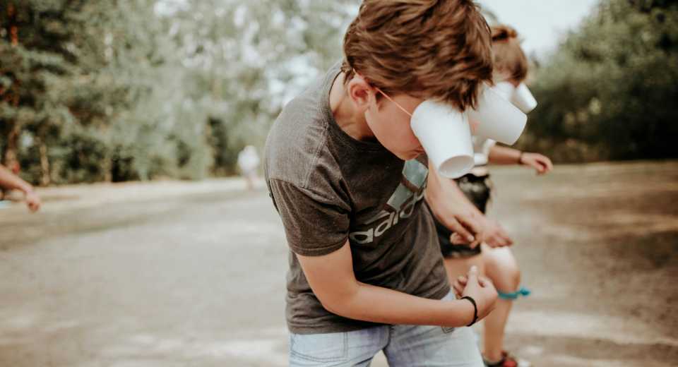 "summer scavenger hunt with teenagers playing a fun outdoor game using plastic cups over their eyes"