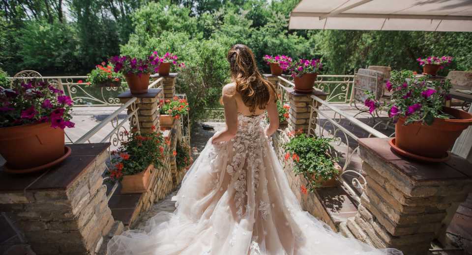 "Sommerhochzeit Braut in einem eleganten Spitzenkleid auf einer blumengeschmückten Terrasse"