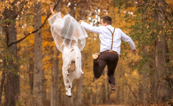 [Uber En="Joyful*newlyweds*jumping*through*an*autumn*forest*at*their*autumn*wedding" De="Fröhliches*Brautpaar*springt*bei*seiner*Herbsthochzeit*durch*einen*herbstlichen*Wald"]